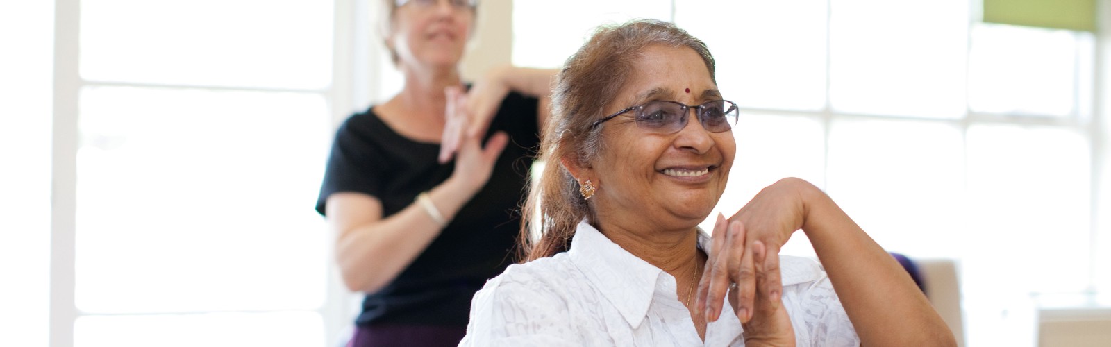 An older Asian lady smiling as she takes part in an ̽Ƶ exercise class